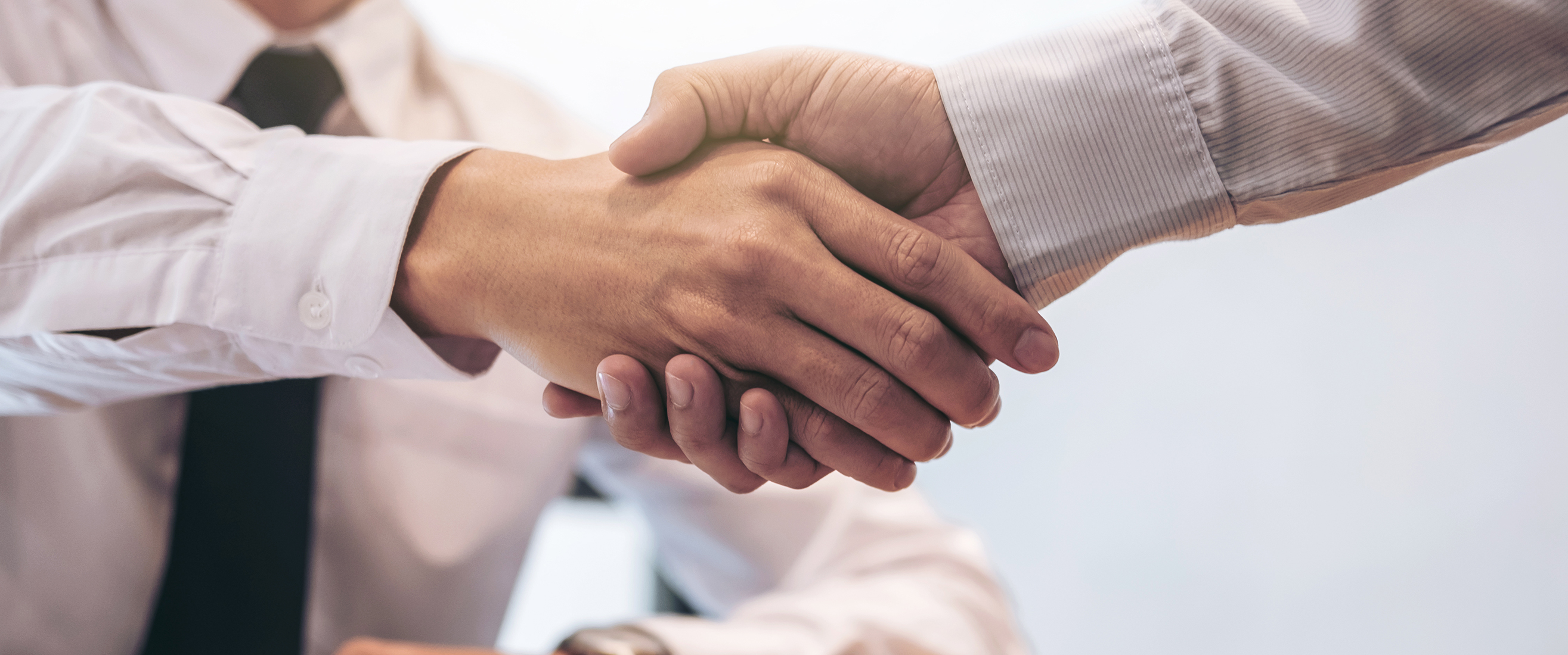 broker agent and customer shaking hands after signing contract documents